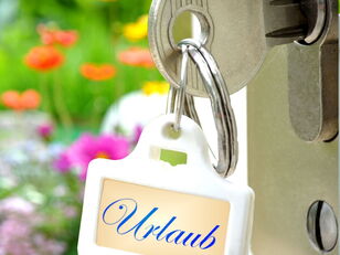 Schlüssel in Tür mit Anhänger "Urlaub"