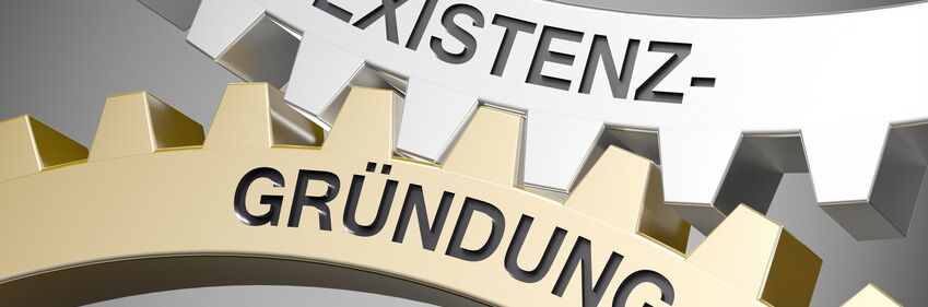 Ausschnitt von Zahnrädern mit Schriftzug "Existenzgründung"