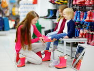 Symbolfoto Einkaufen - Frau probiert Kindern Gummistiefel an