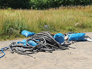 Haufen mit illegal entsorgter Kabelisolation, teilweise in blauen Säcken