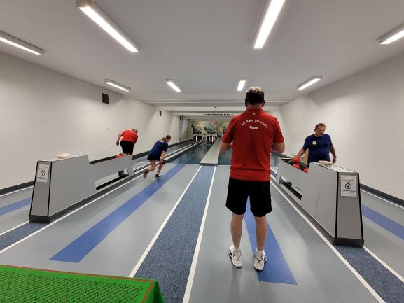 Auf der Kegelbahn. 4 Sportler beim Kegeln