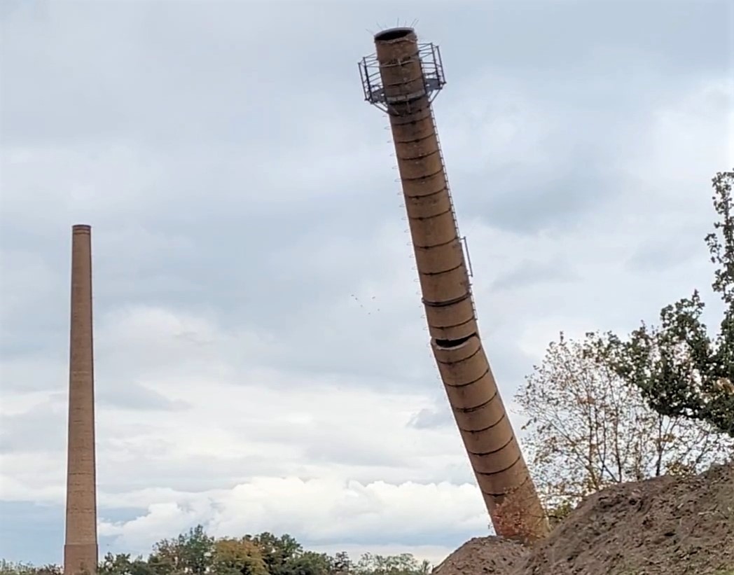 Der Schornstein neigt sich und zerbricht etwa in der MItte, bevor er aufschlägt