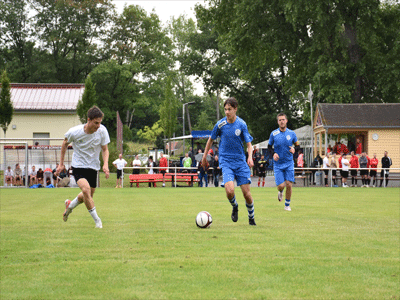 Drei Fußballer spielen auf dem Rasen Fußball.