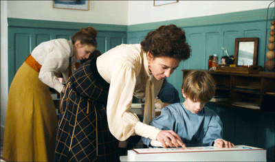 Lehrerin hilft einem Kind welches an der Schulbank sitzt