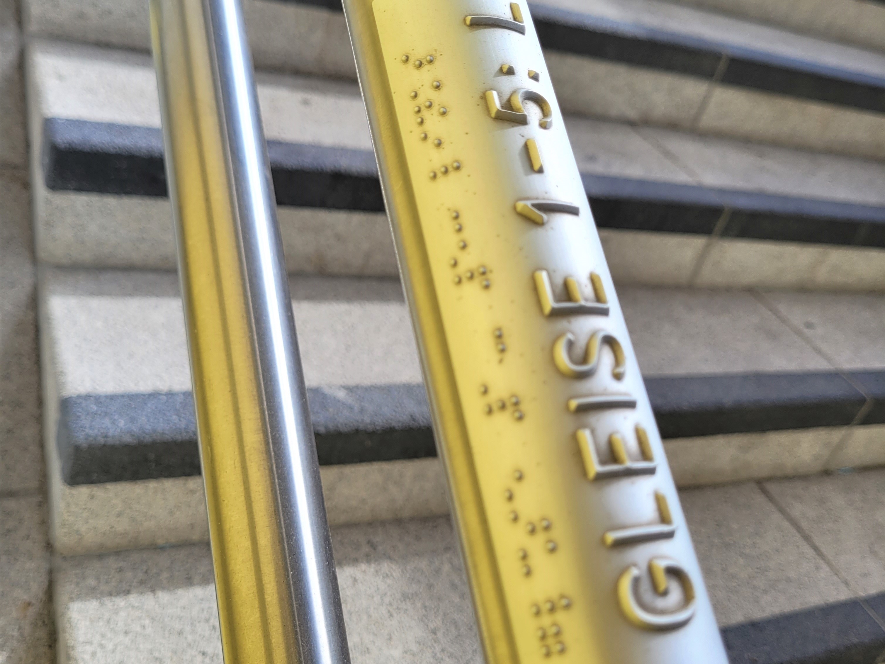 Handlauf im Bahnhof, beschriftet in Profilschrift und Brailleschrift