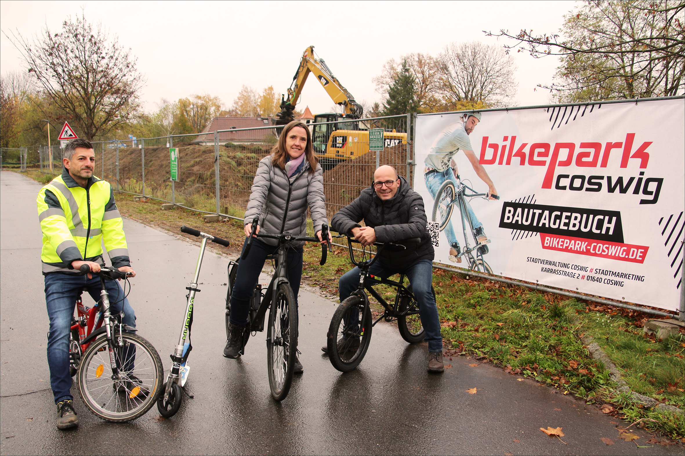 Drei Personen stehen vor dem zukünftigen Bikepark mit Fahrrädern