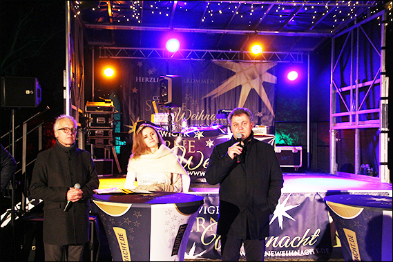 Drei Personen stehen vor einer Bühne und eröffnen die Coswiger Sterneweihnacht.
