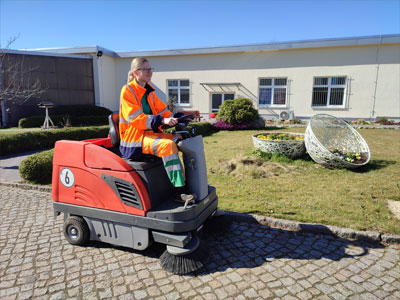 rote Kehrmaschine mit Mitarbeiterin